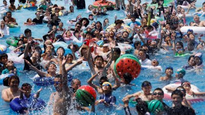 游客们本月1日在东京读卖乐园的室外游泳池戏水消暑。（图取自路透社）