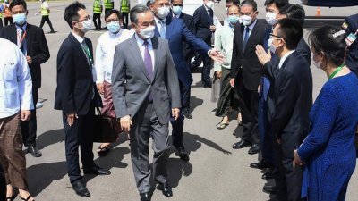 中国国务委员兼外长王毅（中）在周六，抵达缅甸中部城市蒲甘良乌机场。（图取自缅甸军事情报组/法新社）