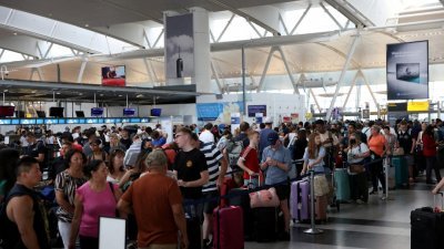 在美国纽约肯尼迪国际机场，大批旅客当地时间周六排队等候办理登机手续。（图取自路透社）