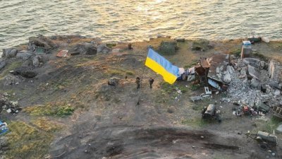 乌克兰军人在蛇岛上升起蓝、黄色的国旗。（图取自乌克兰军方新闻处/路透社）