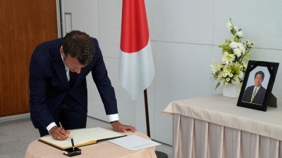 法国总统马克龙11日前往日本驻巴黎大使的官邸，吊唁安倍后在本子上署名。（图取自路透社）
