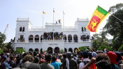 示威者闯入并占领斯里兰卡总理维克勒马辛哈的办公大楼后，挥旗庆祝。（图取自路透社）