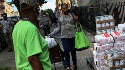 在美国纽约市布朗克斯区大广场教堂外，民众们当地时间周三领取捐赠的食物。（图取自路透社）