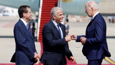 在特拉维夫的本-古里安国际机场举行的欢迎仪式上，以色列总统赫尔佐格看著看守总理拉皮德与美国总统拜登碰拳致意。（图取自路透社）