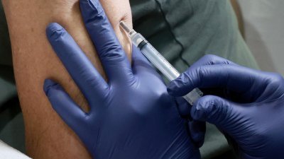 一名医护人员周二在美国佛罗里达州威尔顿庄园的骄傲中心，为一个人接种疫苗以预防猴痘。（图取自法新社）
