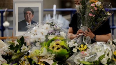 民众在东京自民党总部外为安倍设置的献花台，献上花束哀悼。（图取自路透社）