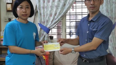 《东方》记者李文艺（右）将热心人士所捐出的善款共3万3280令吉，移交给卢镇忠的遗孀萧佩芬。