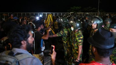 斯里兰卡总统办公区外扎营的反政府示威者周五午夜与安全部队人员对峙。（图取自法新社）
