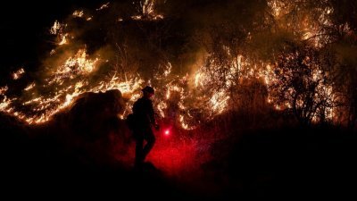 当“橡树大火”在马里波萨附近燃烧时，一名消防员沿著140号高速公路的Midpines公园附近进行扑灭工作。（图取自路透社）