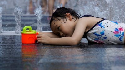 中国江南华南等地区高温天气持续，超过13省市持续发出高温橙色预警。在上海，一个女孩在喷泉里消暑降温。（图取自路透社）