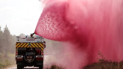 在法国西南部吉伦特地区霍滕斯，消防员喷洒阻燃剂，以扑灭地上的山火。（图取自路透社）