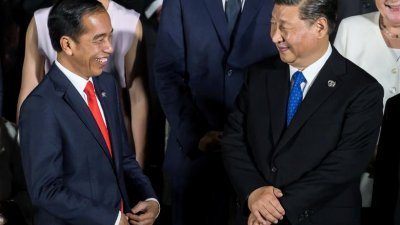 2019年6月28日，在日本大阪举行的 G20峰会期间，印尼总统佐科（左）在拍摄大合照时与中国国家主席习近平交谈。（图取自路透社档案照）