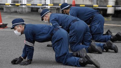 日本警方回到案发现场附近，展开地毯式搜查，寻找嫌犯自制手枪发射的子弹。（图取自共同社/路透社）