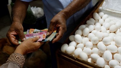 一名在斯里兰卡首都科伦坡卖蛋的小贩，在给顾客找零钱。（图取自路透社）