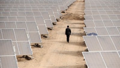 中国新疆维吾尔自治区，一名男子走在一处建设中的大型太阳能发电场的电板中。（路透社档案照）