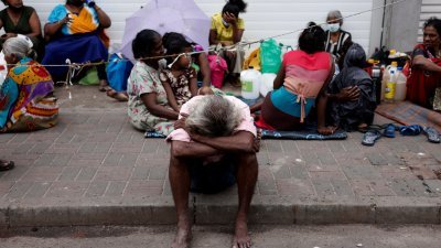 斯里兰卡面临严重经济危机，由于天然气短缺，科伦坡的民众坐在街边排队等候购买煤油。（图取自路透社）