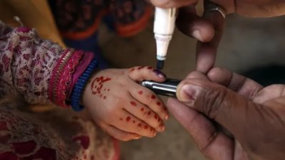 卫生工作人员用特殊笔在已接种疫苗的儿童手指上留下标记。（图取自美联社）