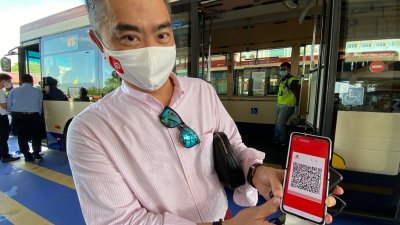 傅子贤向媒体展示justPay系统的应用程式，民众只需下载该应用程式，即可在快捷通巴士上付费。