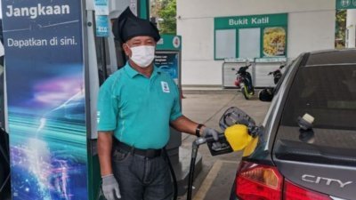 头戴马来传统头巾的油站员工，正为顾客提供添油服务。（照片取自今日马六甲）