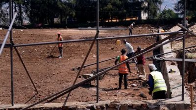 卢旺达的工人在难民住所希望之家边上的空地，建造篮球场供难民娱乐。（图取自英国《卫报》）