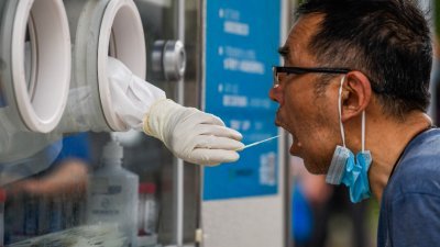 本月22日在上海黄浦区，一名卫生工作者替一名男子采集样本，以进行新冠肺炎病毒检测。（图取自法新社）
