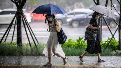 韩国首尔在上周四迎来倾盆大雨，行人纷纷撑著雨伞躲避。在本周，首尔就录得史上首次在6月出现夜间最低气温超过摄氏25度的“热带夜”现象。（图取自法新社）