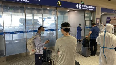 入境旅客等待从北京国际机场，送往集中隔离目的地。（图取自法新社社）