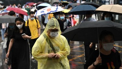 北京市新冠肺炎疫情趋缓，周二繁忙时段，虽然下雨，街上可见民众穿著雨衣或撑著雨伞在路上行走。（图取自法新社）