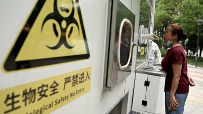 一名妇女周一在北京的一个拭子采集点采集拭子样本，用于检测新冠肺炎病毒。（图取自法新社）