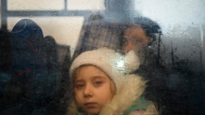 一名逃离乌克兰冲突的女孩当地时间周三，在穿越帕兰卡镇附近的摩尔多瓦-乌克兰边境检查站后，从一辆前往摩尔多瓦首都基希讷乌的巴士内看出去。（图取自法新社）