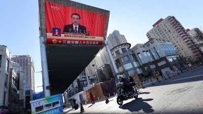 北京街头的大型荧幕，播放中国总理李克强作政府工作报告的新闻。（图取自路透社）