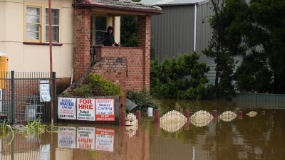 悉尼西南部的卡姆登，居民周二站在阳台处，看著被水淹的家园。（图取自奥联社/路透社）