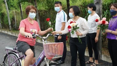 王丽丽（左3）派花给一名骑脚车的妇女，祝她国际妇女节快乐。