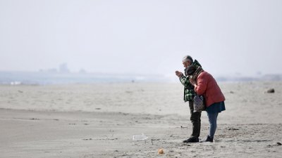 东日本大地震11周年，一对夫妇在宫城县仙台市荒滨区的海滩上，向著大海祈祷，悼念在地震中罹难的人。（图取自共同社/路透社）