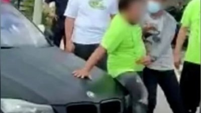 男子以身体阻挡在宝马轿车前，不让拖车员拖走该轿车。