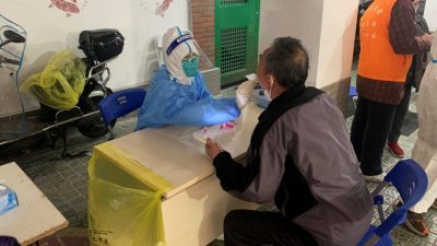 上海市为遏阻疫情，本月15-17日针对重点区域、18-19日针对非重点区域的人群核酸检测。这些街镇内的居民社区封闭48小时并执行两轮检测。图为周六某小区的筛检站，医护人员为居民进行病毒检测。（图取自路透社）