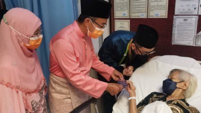 诺阿兹米探望其中一名病人，并分派“开斋钱”（Duit Raya）予其中一名病人。左3为诺阿兹米的助理黄重俊协助翻译。