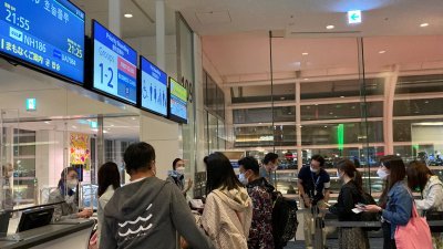 日本“黄金周”假期期间，旅客在东京羽田国际机场排队登上飞往夏威夷的航班。（图取自路透社）