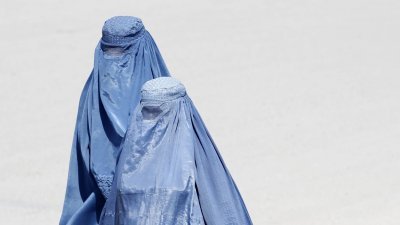 阿富汗女性穿著遮盖全身的蓝色布卡，在喀布尔的街上行走。（路透社档案照）