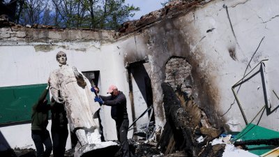 乌克兰哈尔科夫州的斯科沃罗迪尼夫卡村遭炮击，用于纪念哲学家诗人斯科沃罗达的纪念博物馆被毁，工作人员正在移开斯科沃罗达的雕像。（图取自路透社）
