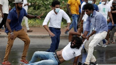 斯里兰卡首都科伦坡周一发生冲突，执政党支持者闯入示威者抗议地点，有者手持棍棒。图中可见亲政府份子拉扯反政府示威者，试图将他拖走。（图取自路透社）