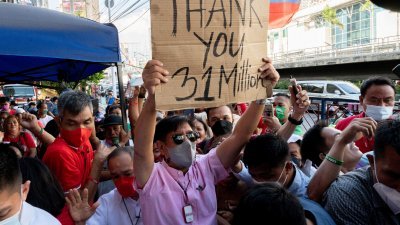 小马科斯周三在马尼拉大都会区曼达卢永市的总部外，举著标语感谢投票给他的3100万名支持者。（图取自路透社）