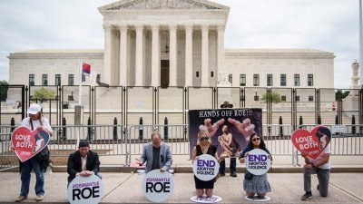 支持（高举横幅者）和反对（跪地祈祷者）堕胎权的民众当地时间周三，在美国最高法院外各自以自己的方式表达诉求。（图取自法新社）