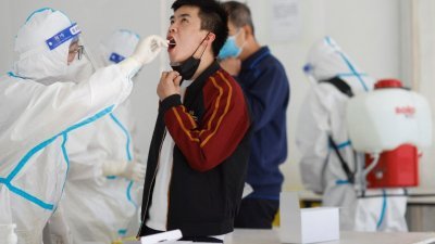 全副武装的防疫人员正在为北京市民进行核酸检测。（图取自路透社）