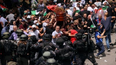 以色列警察挥舞著警棍冲向希琳的葬礼队伍，擡棺的人努力避免棺木掉到地上。（图取自路透社）