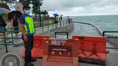 槟岛市政厅执法员于周一下午，暂时关闭被海水淹没的旧关仔角海堤走道。