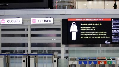 成田国际机场出发大厅关闭的闸门旁，电子布告以多种语言给民众予以提醒。（路透社档案照）