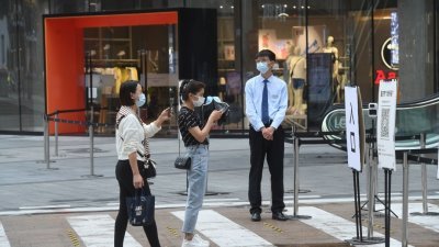 在重庆市江北区，市民本月11日用手机扫重庆市“场所码”进入商场，商场工作人员也严格检查进入人员的健康码和行程码。（图取自中新社）