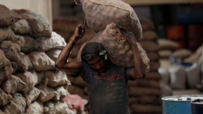 斯里兰卡经济危机引发粮食短缺，尽管政府承诺将努力解决问题，但民众都不对此抱有信心。图为一名男子在市场上扛著两袋洋葱。（路透社档案照）