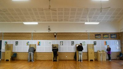 澳洲周六迎来大选投票日，选民们在韦弗利郊区投票站投下手中选票。（图取自路透社）